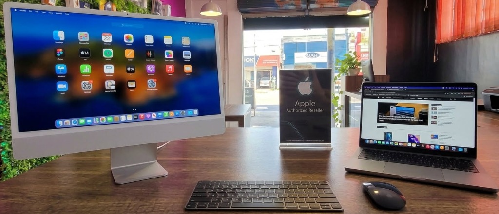 iMac e MacBook Pro expostos lado a lado com placa Apple Authorized Reseller na bancada da Info Fácil